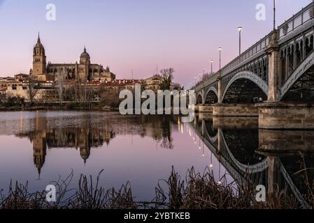 Malerischer Blick auf Salamanca mit der Kathedrale und der Eisenbrücke, die sich bei Sonnenuntergang im Tormes River spiegelt. Castilla Leon, Spanien, Europa Stockfoto