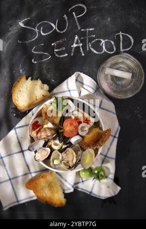 Präsentation einer Suppe mit Meeresfrüchten auf schwarzem Hintergrund mit Schrift Stockfoto