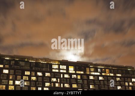Moderner Apartmentblock in der Nacht, hinter dem der Mond aufgeht Stockfoto