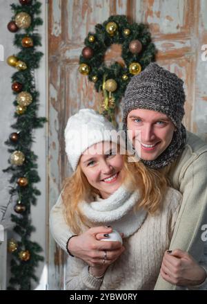 Junges glückliches Paar umarmt vor weihnachtlichem Hintergrund Stockfoto