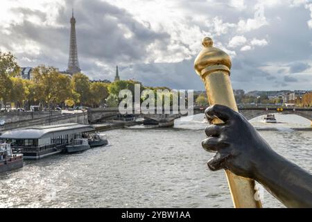 Ein Detail der alten Alexander III Brücke über die seine, mit dem Eiffelturm im Hintergrund unter einem dramatischen Himmel, Paris, Frankreich Stockfoto