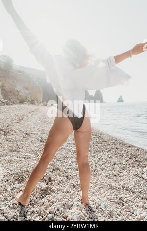 Frau in einem weißen Hemd und schwarzem Badeanzug am Strand Stockfoto