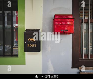 Briefkästen an einer Wand in verschiedenen Farben zwischen benachbarten Häusern. Stockfoto