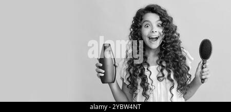 Schockiert Kind lockiges Haar halten Kamm und Shampoo-Flasche. Teen Schönheit Frisur. Kid girl Haarpflege, horizontales Poster. Banner-Kopfzeile mit Kopierbereich. Stockfoto