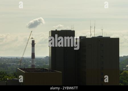 Arbeiten Sie oben auf dem Kamin. Ein hängender Bagger an einem Kran zerstört einen Schornstein. Drohnenansicht des Abbruchs des Schornsteins, Bagger arbeitet mit Rauch Stockfoto