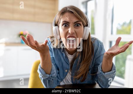 Wütende Frau, die die Kamera anschreit, Videokonferenz zu Hause mit Küche im Hintergrund Stockfoto