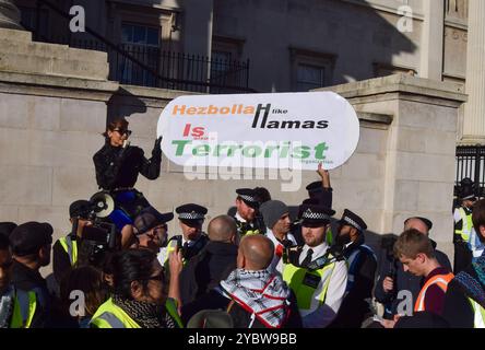 London, Großbritannien. Oktober 2024. Israelische Anhänger halten während eines Gegenprotests ein Anti-Hisbollah- und Anti-Hamas-Plakat. Tausende palästinensischer Demonstranten versammelten sich auf dem Trafalgar-Platz und forderten einen Waffenstillstand, während Israel seine Angriffe auf Gaza fortsetzt. Quelle: Vuk Valcic/Alamy Live News Stockfoto