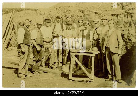 Ursprünglich aus den frühen 1900er Jahren stammende Postkarte mit einer Gruppe von Arbeitern, vielleicht auch Archäologen, mit einer Auswahl an antiken Tontöpfen, die vielleicht bei Steinbrucharbeiten, Bergbau oder Straßenbau entdeckt wurden. Archäologische Grabungsfunde, die auf einem Tisch für ein Foto angezeigt werden. Archäologische Ausgrabungen. Circa 1910, Großbritannien Stockfoto