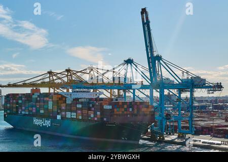 Barcelona. Espain - 20. Oktober 2024: Frachtschiff gefüllt mit Containern im Hafen von Barcelona, mit gelben und blauen Kränen. Ausgezeichnetes Image für Themen auf fo Stockfoto