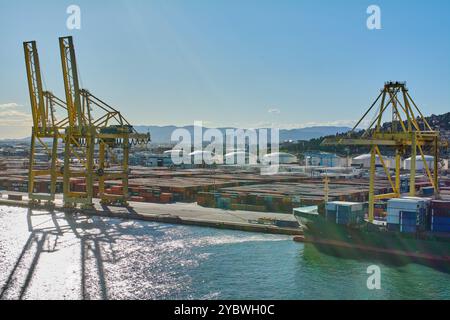 Barcelona. Espain - 20. Oktober 2024: Hafen von Barcelona, wo mehrere Kräne und ein Frachtschiff voller Container entladen werden. Stockfoto