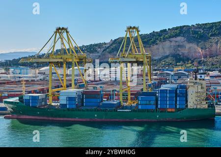 Barcelona. Espain - 20. Oktober 2024: Bild des Hafens von Barcelona, mit einem Frachtschiff voller Container, das mit Ladekränen angedockt ist. Stockfoto