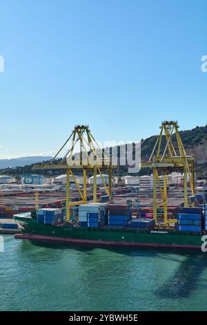 Barcelona. Espain - 20. Oktober 2024: Frachtschiff im Hafen von Barcelona, umgeben von Kränen, während Container entladen werden. Ein Bild, das Effizienz symbolisiert Stockfoto