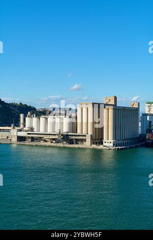 Barcelona. Espain - 20. Oktober 2024: Aus der Vogelperspektive auf den Industriehafen von Barcelona mit Getreidesillos unter blauem Himmel und ruhigem Meer. Stockfoto