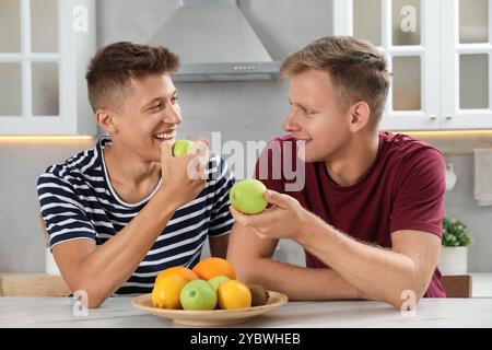 Glückliche Brüder essen Äpfel am Tisch in der Küche Stockfoto