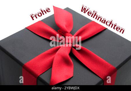 Weihnachtsgeschenk mit rotem Band. Übersetzung der deutschen Wörter bedeutet frohe Weihnachten. Grußkarte. Stockfoto