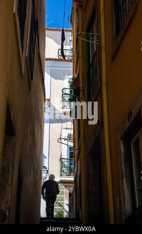 Eine Person läuft eine enge Straße in Alfama, Lissabon, Portugal. Stockfoto