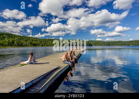 Eine Gruppe von Menschen, die sich an einem sonnigen Tag am See Sognsvann in Oslo, Norwegen entspannen und die ruhige Sommerlandschaft und das ruhige Wasser genießen. Stockfoto