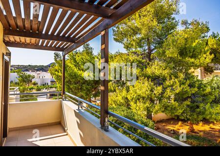 Balkonblick mit Holzpergola mit Blick auf üppige grüne Bäume und Resort an sonnigen Tagen auf Kreta. Stockfoto