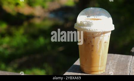 Eiskaffee in Plastikbecher mit Schlagsahne, auf Holztisch gestellt, Stockfoto