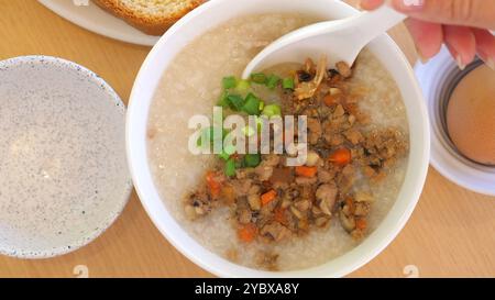 Nahaufnahme einer Schüssel mit frisch zubereitetem Congee, garniert mit gekochtem Hackfleisch Stockfoto