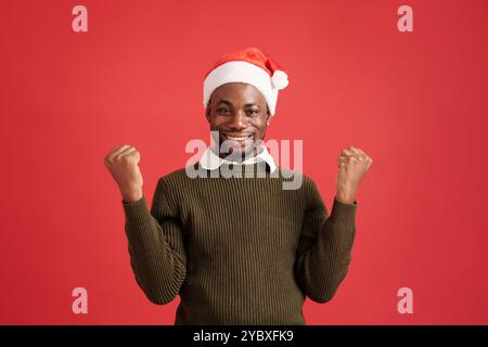 Porträt eines Mannes mit Weihnachtsmütze vor rotem Hintergrund Stockfoto