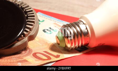 Nahaufnahme von Gas- und Stromrechnungen, Glühbirne und Gas mit Euro-Banknoten und rotem Hintergrund. Stockfoto