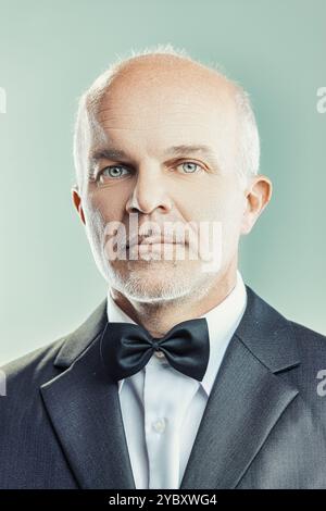 Ein selbstbewusster, reifer Geschäftsmann in scharfem Anzug und Fliege strahlt Professionalität und Erfahrung aus und strahlt Vertrauenswürdigkeit und Entschlossenheit aus. Hochformat ca. Stockfoto