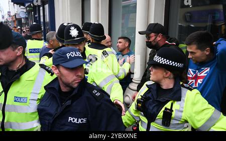 Brighton UK 7. August 2024 - Ein örtlicher Händler, der in der Nähe arbeitete, wird von den Protesten verwickelt und wird von der Polizei geschützt, da Antirassisten gegen die jüngsten rechtsextremen Demonstrationen in ganz Großbritannien protestieren . Seit der Ermordung von 3 Kindern in Southport im Juli gab es Rassenunruhen : Stockfoto