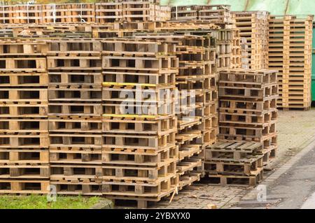 Viele Holzpaletten sind übereinander gestapelt und bilden eine Wand in einem Lagerbereich Stockfoto