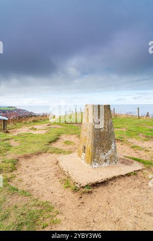 Trigpunkt oder Triangulationspunkt auf dem Gipfel des Beeston Hill in Sheringham, Norfolk, Großbritannien im Hochformat Stockfoto