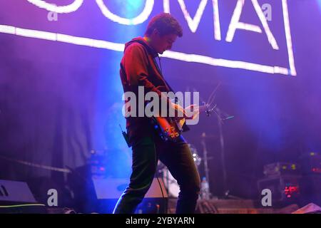 Rockgitarrist spielt E-Gitarre und singt auf der Bühne während eines Konzerts unter farbigen Scheinwerfern und Mikrofon Stockfoto