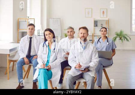 Junge Ärzte sitzen auf Stühlen in der Klinik während eines medizinischen Seminars oder einer Konferenz im Besprechungsraum Stockfoto