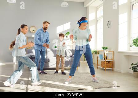 Die Mutter mit verbundenen Augen erwischt ihre Familie beim Verstecken und Suchen zu Hause. Stockfoto