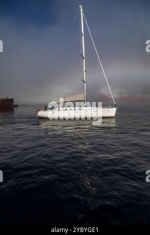 Segelboot erster Spieler im Hafen von Bergen, Norwegen. Ein Herbsttag mit dickem Nebel rund um den Hafen Stockfoto