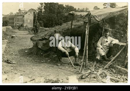 Postkarte aus der Zeit des 1. Weltkriegs mit französischen Soldaten am Beginn des Krieges, September 1914, mit getarnter provisorischer Unterkunft, Verteidigung einer Brücke und einer Stadt/einem Dorf. Soldaten warten und bereiten sich auf Kriegsbombardements vor. Ein Soldat mit einem Bajonett auf seinem Gewehr patrouilliert die Brücke, um die Stadt/das Dorf zu bewachen. Unbekanntes Regiment. Frankreich datiert im September 1914 an der Front. Stockfoto