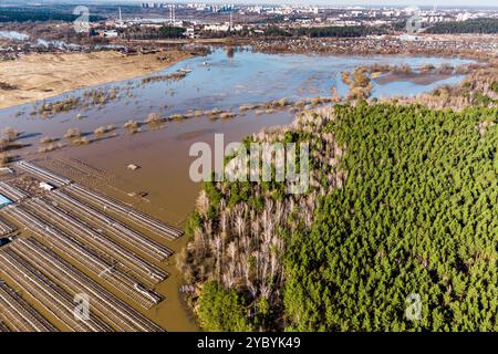 Fliegen über Ackerland, überflutet von Quellwasser, Gewächshäusern und Wald darunter Stockfoto