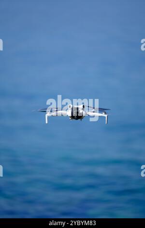 Mini-Drohne fliegt an einem sonnigen Sommertag über das Meer, DJI Mini Pro 4 Stockfoto