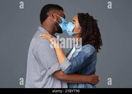 Romantisches Schwarzes Paar Küsst Sich In Medizinischen Schutzmasken Stockfoto