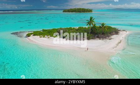 Aus der Vogelperspektive einer jungen Frau, die an einem weißen Sandstrand einer kleinen einsamen Insel in der Mitte einer türkisfarbenen Lagune auf den malediven spaziert. Stockfoto