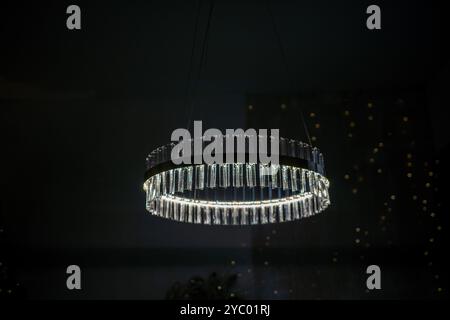 Ein großer, klarer und glänzender Kronleuchter hängt von der Decke. Das Licht leuchtet und beleuchtet den Raum. Stockfoto