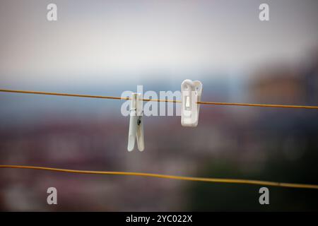 Nahaufnahme von zwei Wäschespins auf einer Wäscheleine vor einem verschwommenen urbanen Hintergrund - Wäscherei, Trocknung und Haushaltsarbeit Konzept Stockfoto