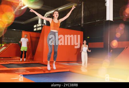 Glückliche Frau mittleren Alters, die auf Trampolinen in einem Sporthalle trampoliniert und springt, Workout und modernes Unterhaltungskonzept Stockfoto