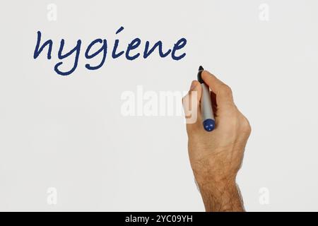 Ein Mann schreibt "Hygiene" auf weißes Tafel mit blauem Marker. Leerzeichen für Text. Stockfoto