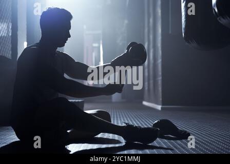 Mann, Boxhandschuhe und Training als Profi-Boxer in Silhouette im Fitness-Center zur Herausforderung. Männlicher Mensch, Athlet und Macht zum Kampf Stockfoto