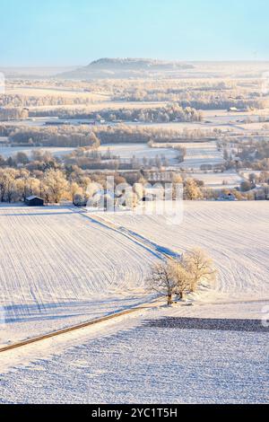 Malerische Aussicht auf eine ländliche Winterlandschaft mit einer Straße auf den verschneiten Feldern Stockfoto