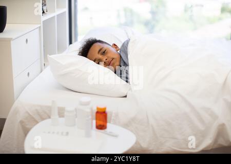 Junger afrikanischer Junge, der im Bett liegt und sich von Krankheit erholt Stockfoto