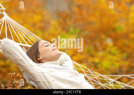 Frau, die auf einer Hängematte im Herbstwald liegt Stockfoto