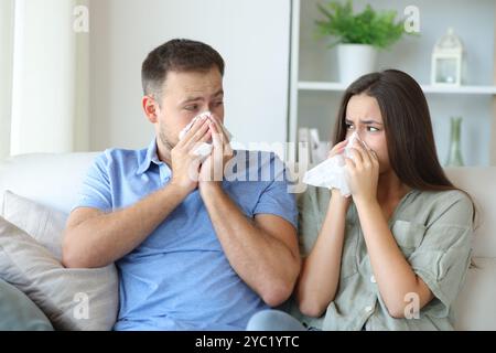 Ein krankes Paar zu Hause, das sich auf der Couch ansieht Stockfoto