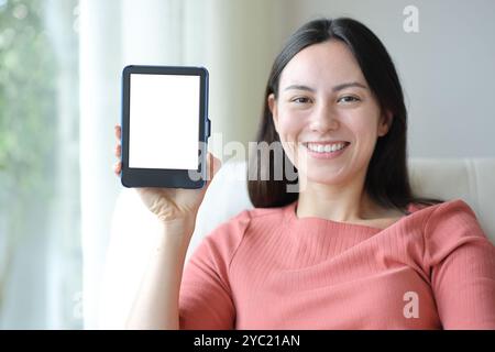 Glückliche asiatische Frau, die einen leeren E-Mail-Bildschirm vor der Kamera zeigt und zu Hause in asofa sitzt Stockfoto