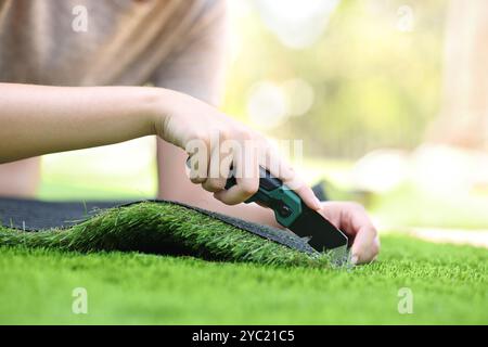 Clos eup einer Frau, die mit der Hand Gras in einem Garten schneidet und installiert Stockfoto